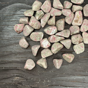 Example of Thulite in Quartz tumble stone - pale green/grey stone with some spots of pink - on a black background