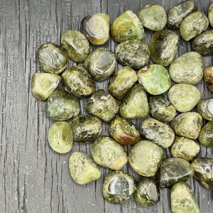 Example of Green Garnet A/A Grade tumble stone - green with hints of black - on a black background